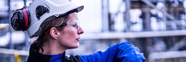 female oil refinery worker leaning on railing